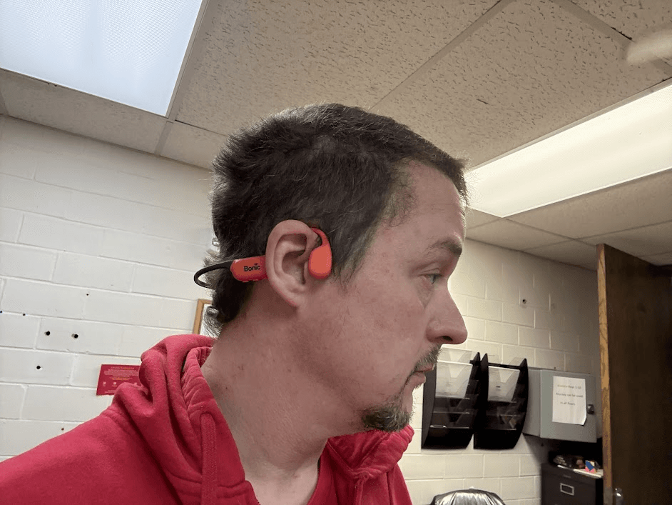 Tony Simons side-profile testing Bonic bone conduction audio equipment